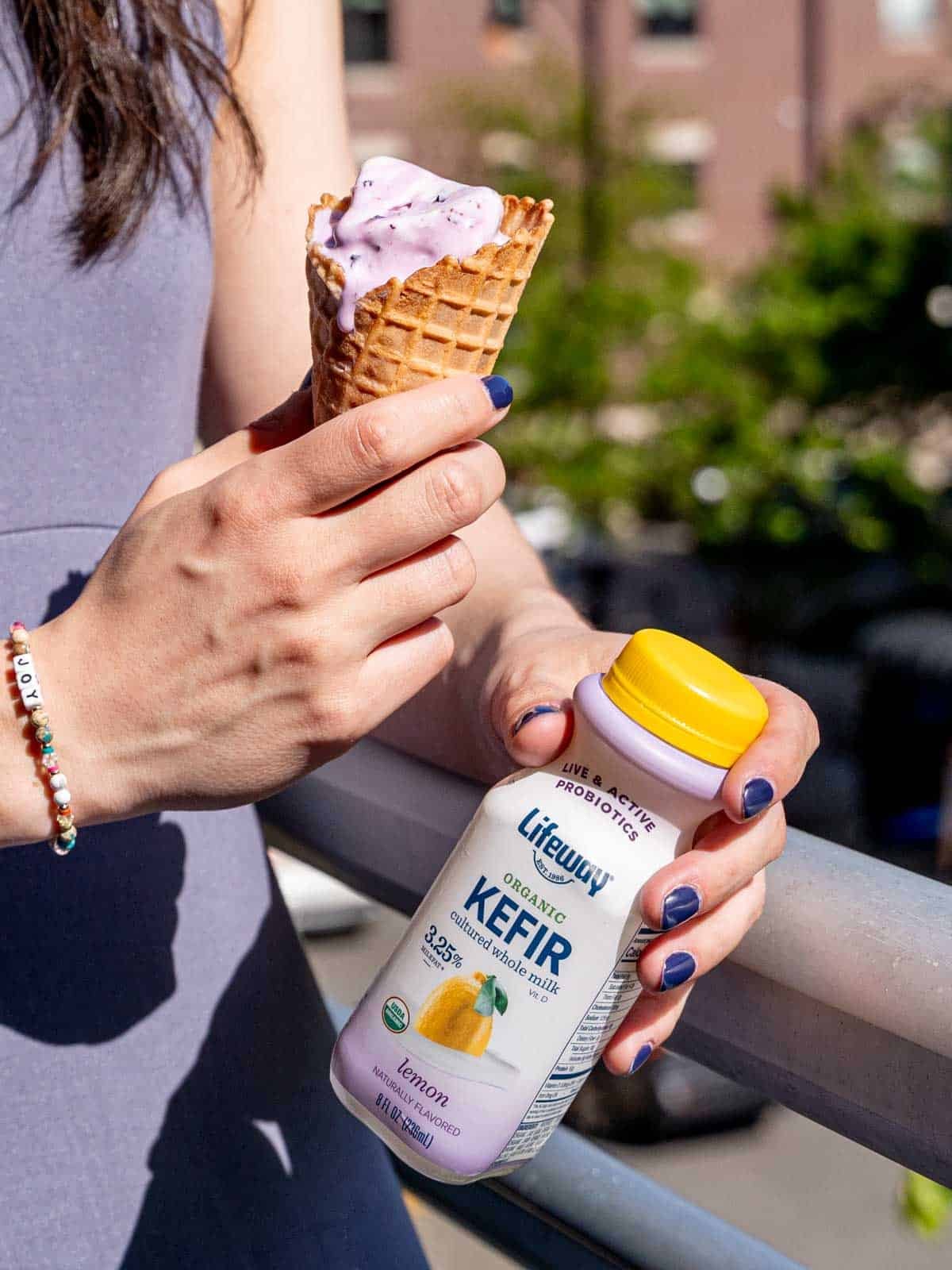 Kayla Burton holding an ice cream cone in one hand and a mini Lifeway Lemon Kefir bottle in the other hand.