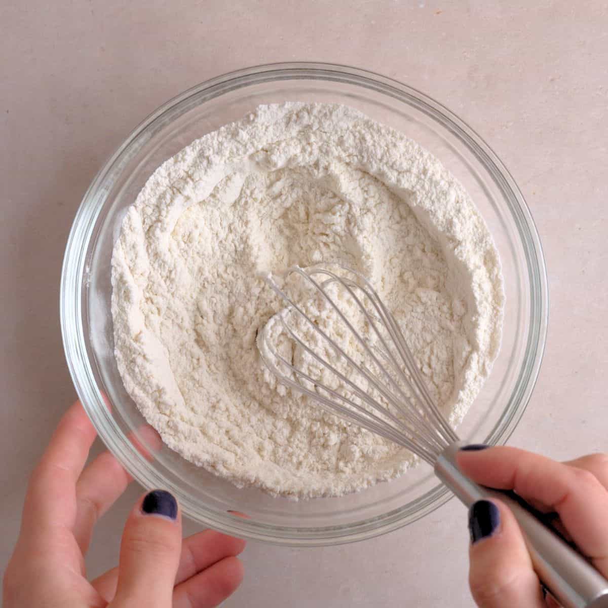 Flour, baking soda, and salt being whisked in a bowl.