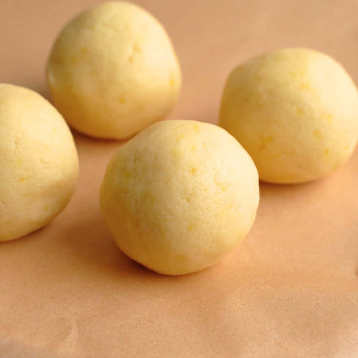 Lemon cookie dough balls on a sheet of parchment paper.