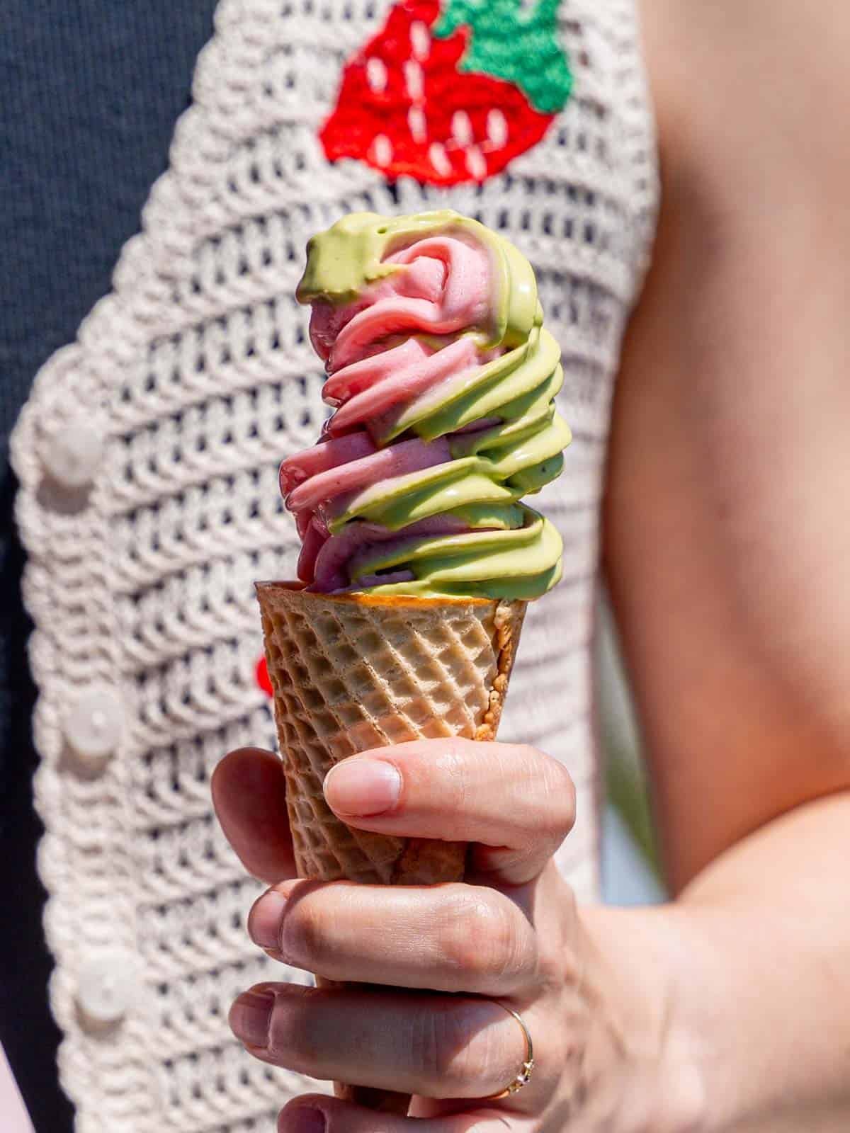 Strawberry matcha ice cream swirled in a sugar cone.