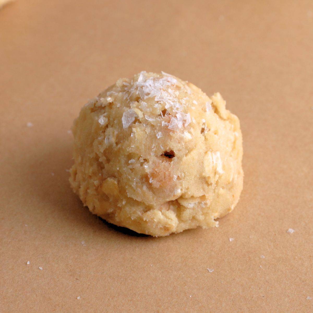 Dough ball for caramel oatmeal cookies topped with sea salt.