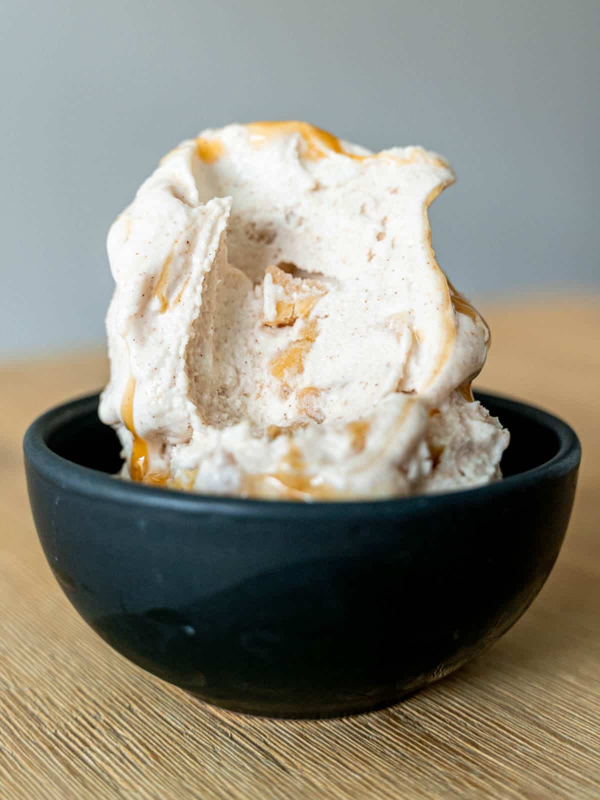 A scoop of caramel apple pie cheesecake ice cream with a bite taken out of it.