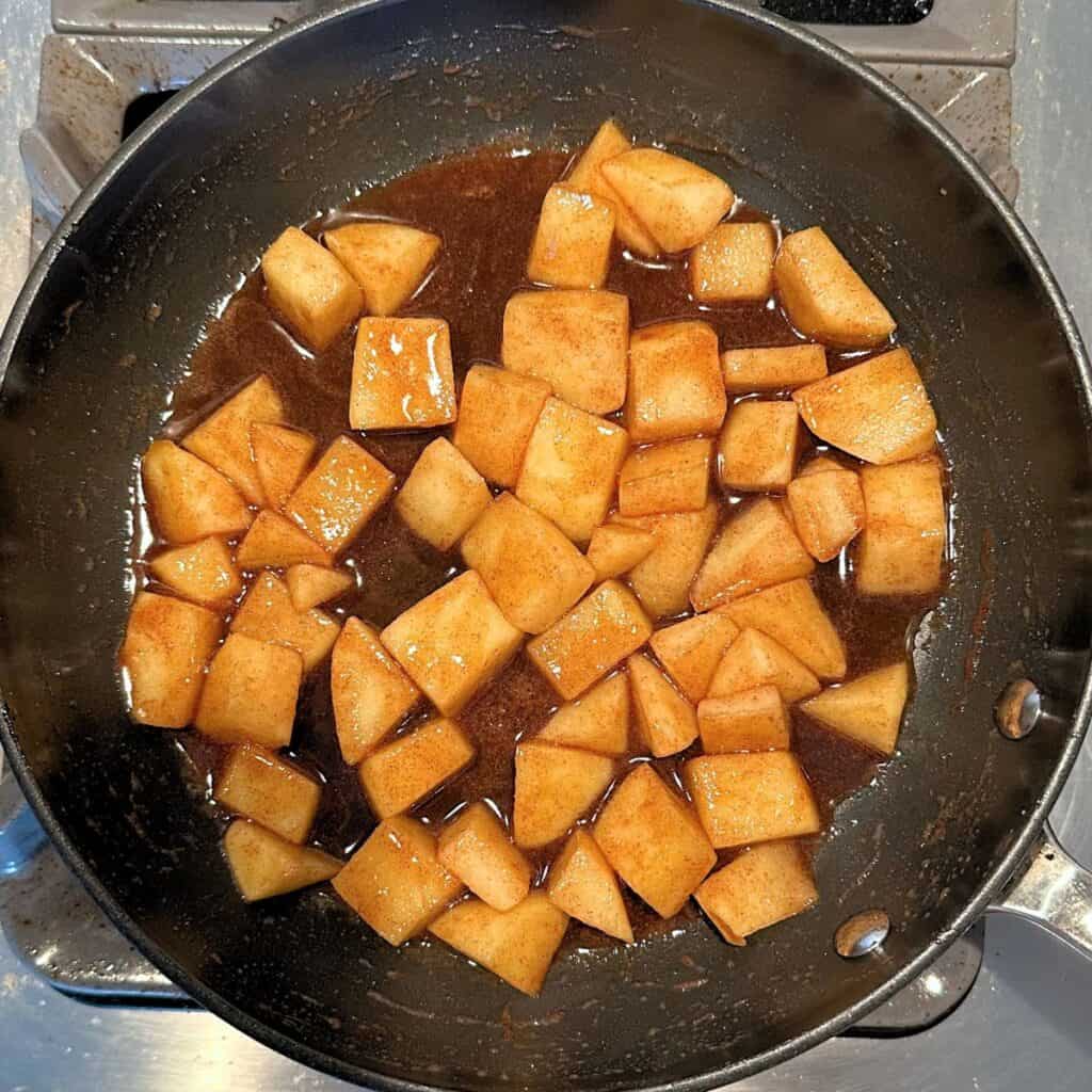 Apples, butter, brown sugar, and cinnamon getting cooked in a skillet.