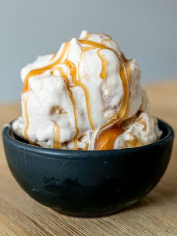 Apple cheesecake ice cream in a bowl with caramel sauce drizzled on top.