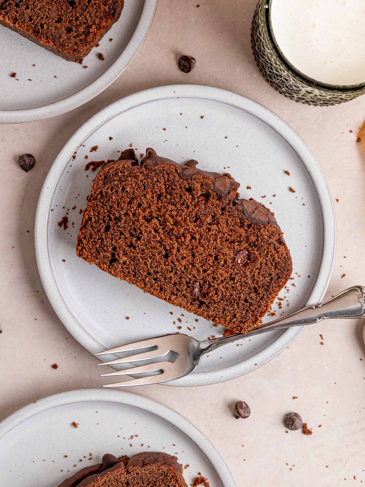 A slice of chocolate loaf cake on a plate with a fork.