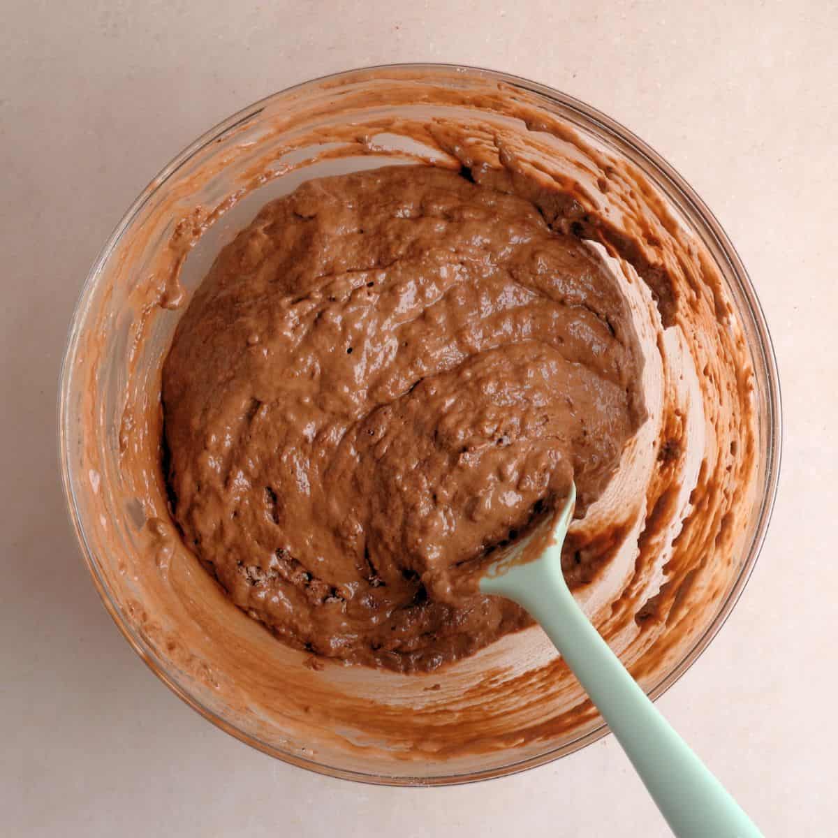Chocolate cake batter in a bowl with a spatula.