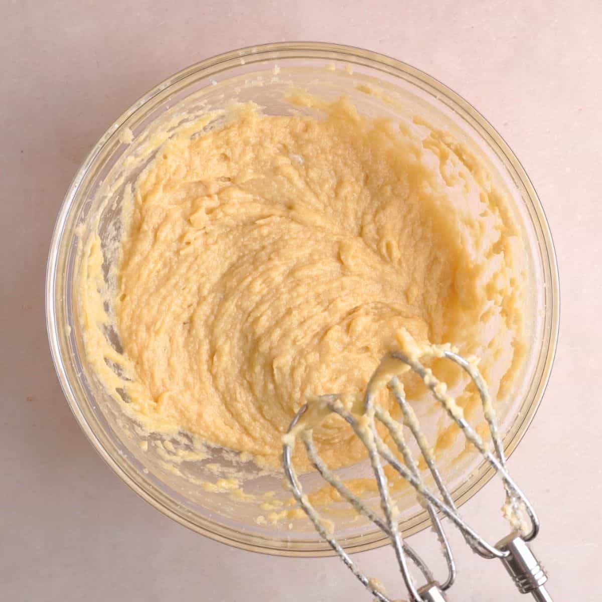 Butter, sugars, eggs, and vanilla extract creamed together in a bowl.