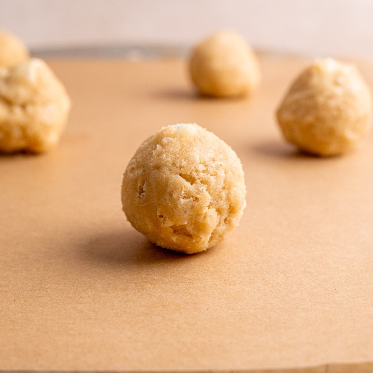 Cookie dough balls with marshmallows and Rice Krispies on a baking sheet.