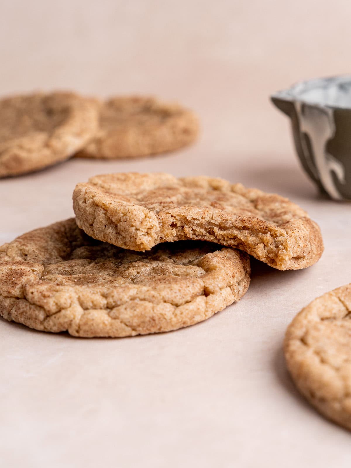 Stacked snickerdoodle cookies with a bite taken out of the top cookie.