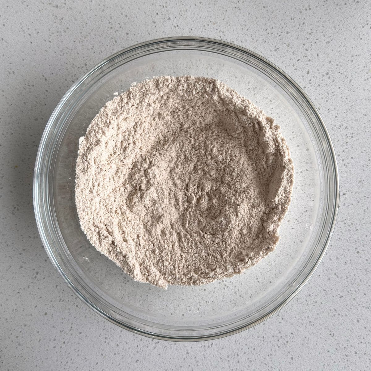 Flour, baking powder, salt, cinnamon, nutmeg, and ginger mixed in a bowl.