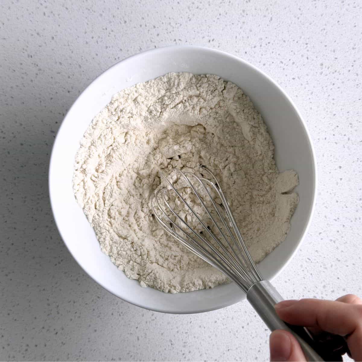 Flour, baking powder, cinnamon, and salt mixed together in a bowl.