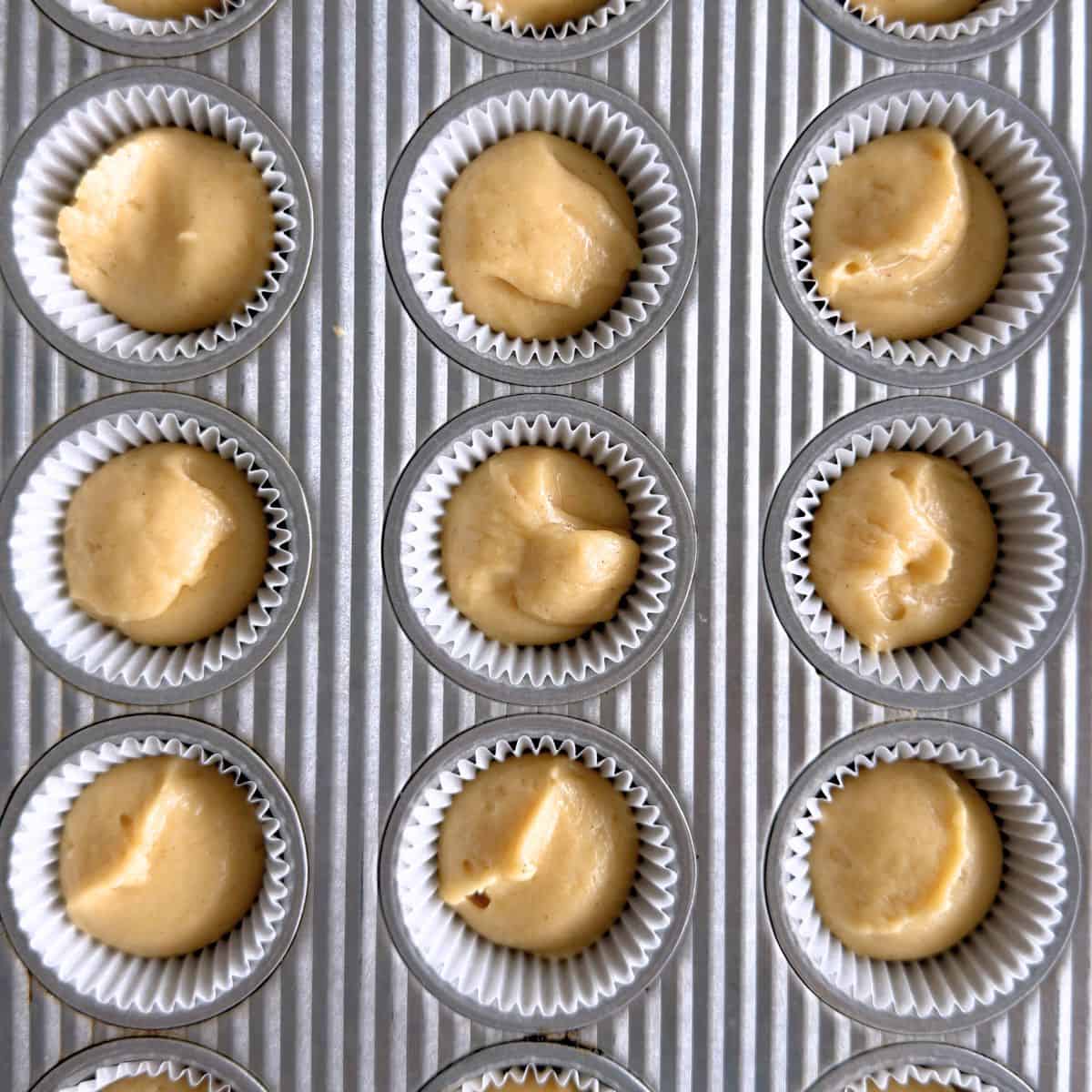 Mini muffin cups filled evenly with honey muffin batter.