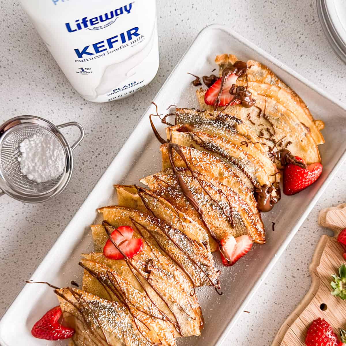 Nutella and strawberry crepes on a plate next to a bottle of Lifeway kefir.
