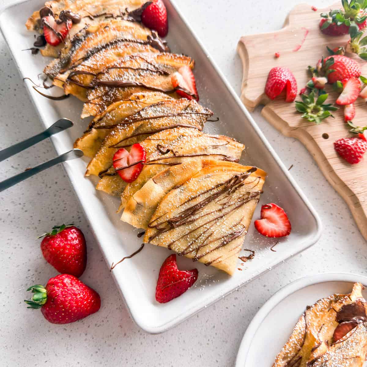 Strawberry Nutella crepes stacked on a plate.