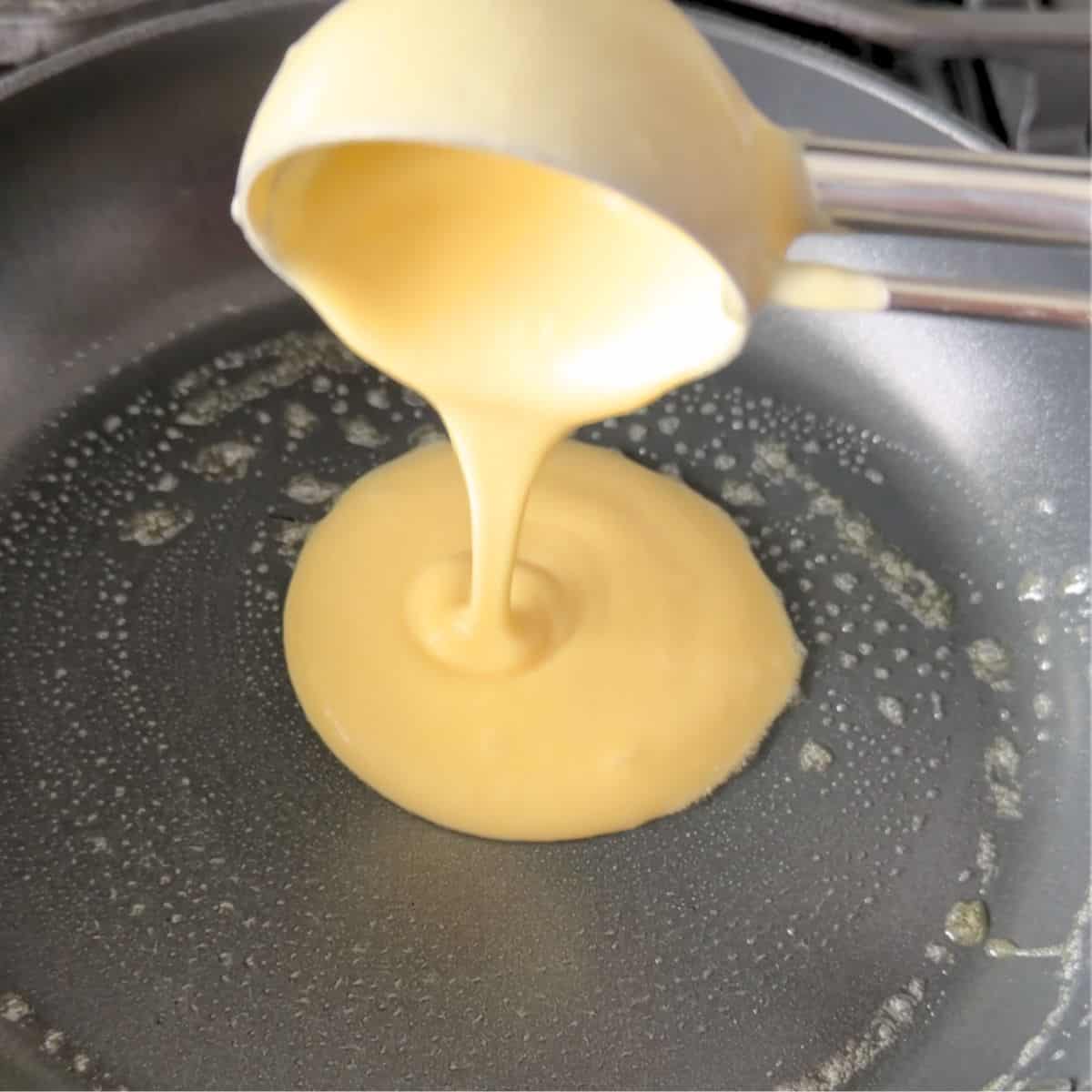 Pouring crepe batter onto a buttered pan.