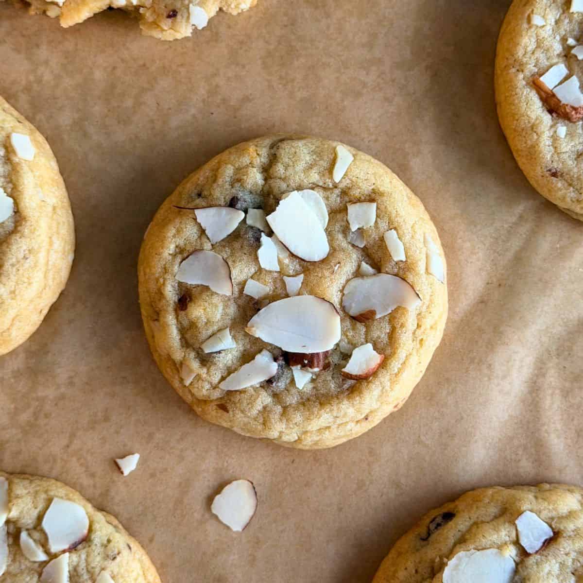 An orange almond chocolate chip cookie with sliced almonds on top.