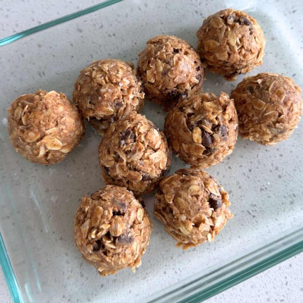 Almond butter energy bites with flaky salt in a Pyrex container.